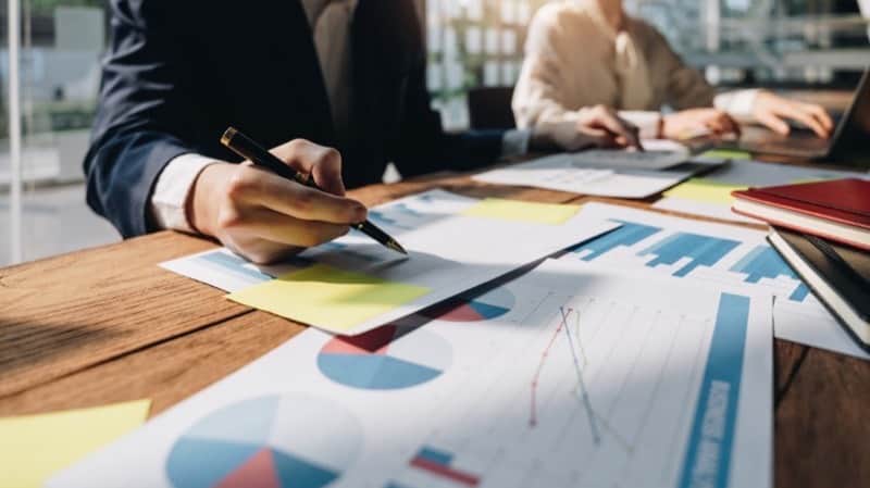 Marketer reviewing Google Ads AI Max charts and performance reports with a pen
